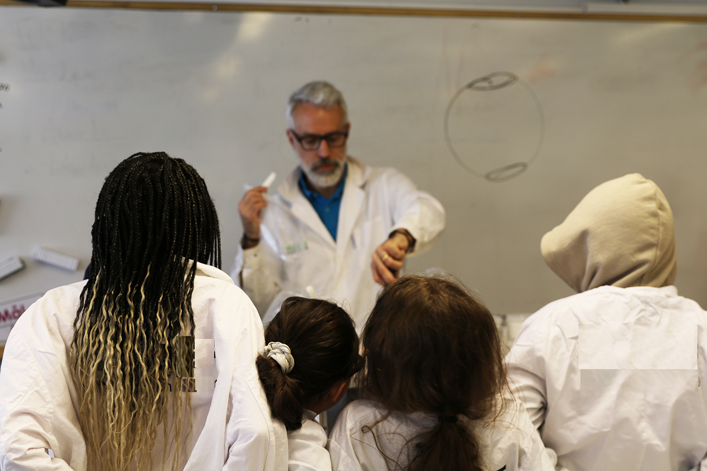 En lärare som gör ett kemiexperiment framför en grupp av elever. 