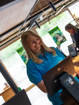 Universeum personal står bakom en kassa och ler.