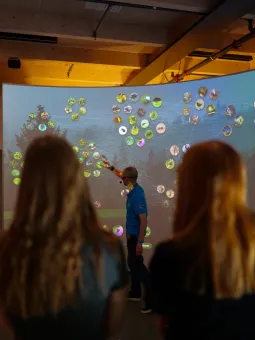 En pedagog visar upp djurs relationer till naturen på en skärm.