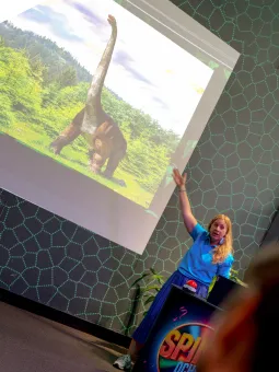 En från personalen på Universeum presenterar en dinosaurie på en skärm.