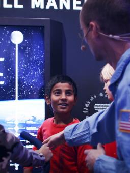 En guide visar montern "cykla till månen" för några entusiastiska barn inne i utställningen Rymdresan.