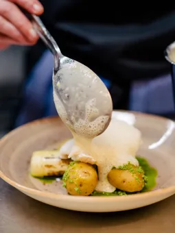 En portion med fisk läggs varsamt upp på en fin tallrik i Universeums fina restaurang.
