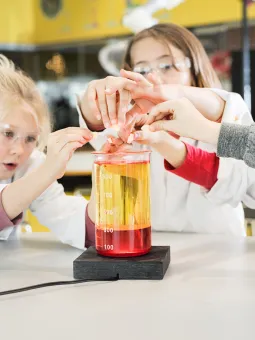 Flera barn experimenterar inne i Universeums kemilabb iklädda rockar och skyddsglasögon.