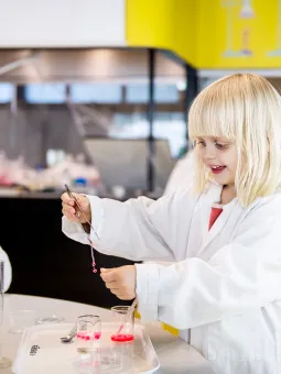 Ett barn är inne i Kemilabbet och utför ett experiment med slajm.