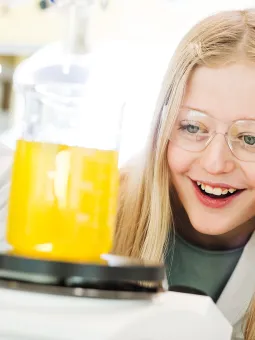 Två äldre barn som experimenterar inne i Universeums kemilabb. På sig har de både glasögon och labbrockar 