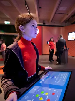 Flicka tittar på väggskärm vid interaktiv station