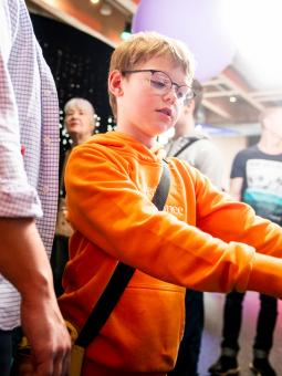 En kille i en klar, orange tröja utforskar en monter inne i utställningen Mathrix.