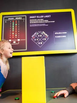 En pappa och hans barn spelar Jaget eller laget, en interaktiv monter inne i Mathrix.