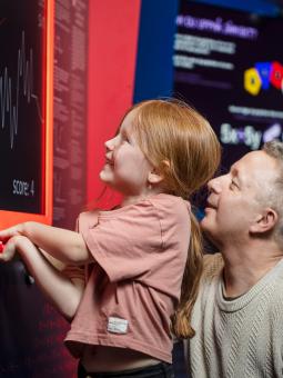 En flicka och hennes pappa utforskar en monter inne i utställningen Mathrix.