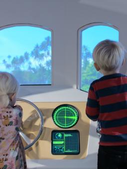 Två barn styr båten ADA mot nya äventyr nere i Miniverseum. En utställning för våra yngsta besökare.