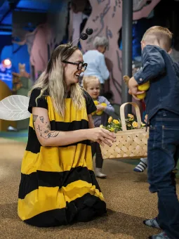 En kvinna i bi-dräkt och flera barn som leker.
