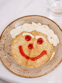 En pannkaka med ett glatt ansikte ligger uppdukad på en tallrik. 