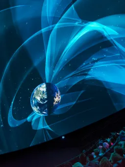En publik sitter och tittar fascinerat på en föreställning inne i Universeums visualiseringsdom. 