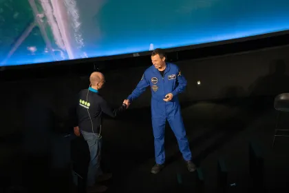 Två män som hälsar på varandra, den ena bär astronautkläder.