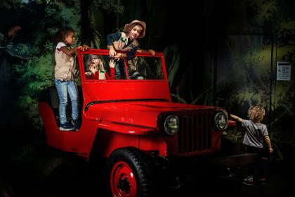 Tre barn som leker i en röd jeep.
