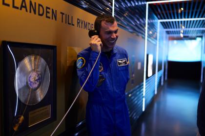 En glad man klädd i astronautdräkt som pratar i en telefon.