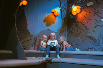 Tre barn sitter och läser böcker nere i Miniverseum, en upplevelse för Universeums yngsta besökare.