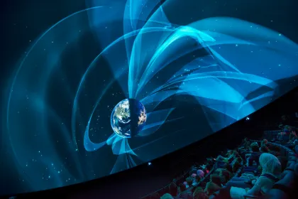 En publik sitter och tittar fascinerat på en föreställning inne i Universeums visualiseringsdom.