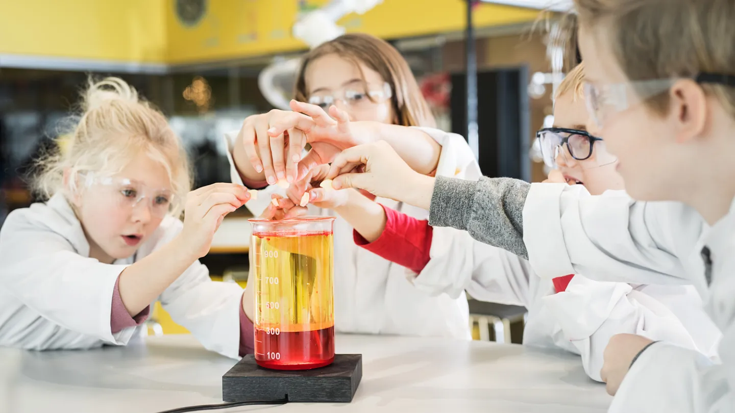 Flera barn experimenterar inne i Universeums kemilabb iklädda rockar och skyddsglasögon.