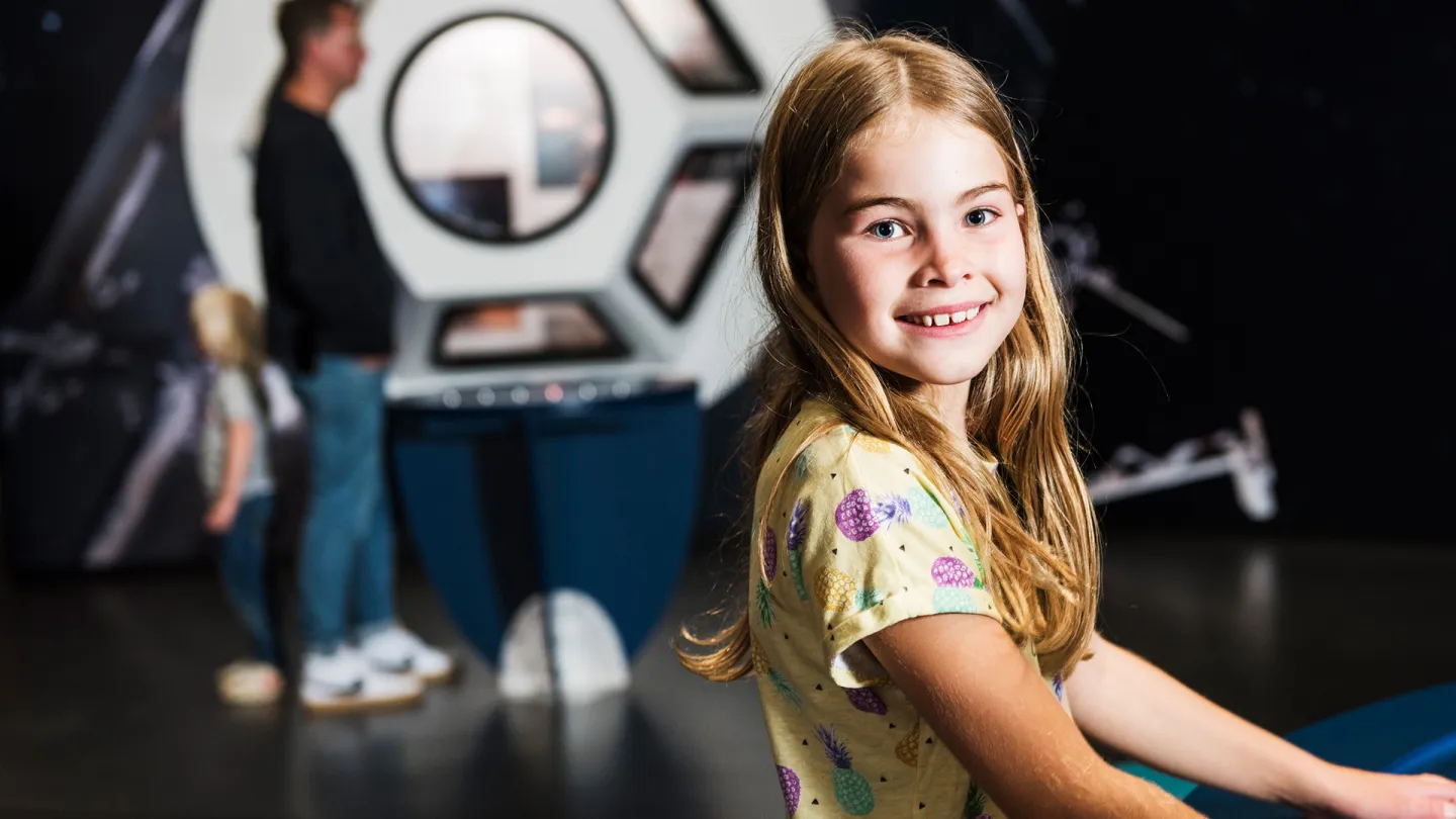 Ett glatt barn inne i Universeums utställning Rymdresan. 