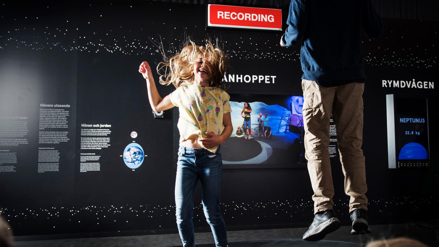 Två barn som hoppar månhoppet inne i Universeums utställning Rymdresan.