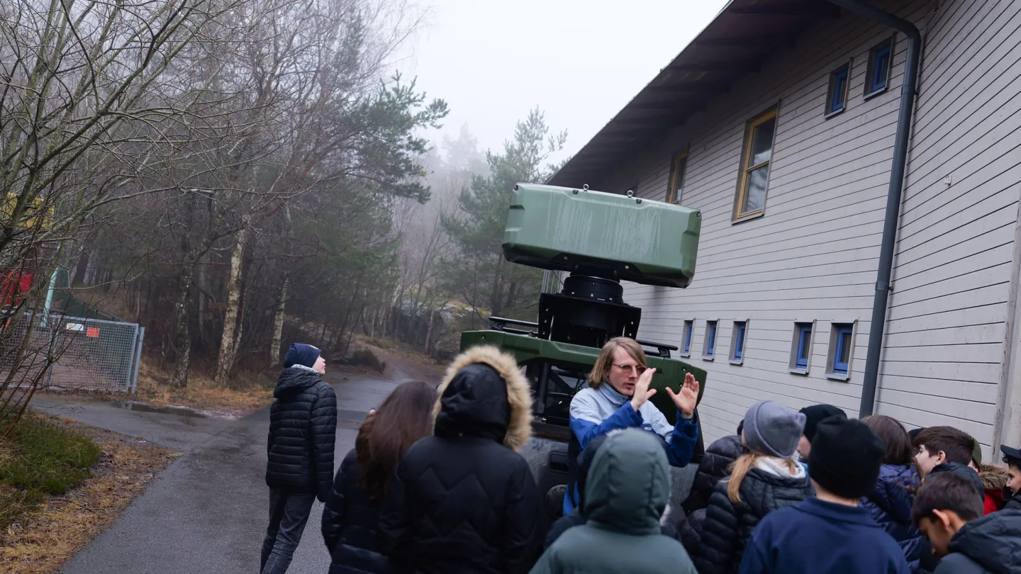 En grupp elever står i en grupp utanför ett hus.